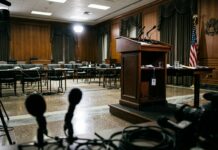Patrick Witt dimite del Consejo Cripto de la Casa Blanca Podio vacío en una sala de prensa institucional con suelos pulidos y micrófonos desenfocados (imagen generada por IA)