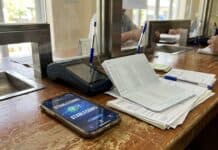 Stablecoins: Die BIZ erwägt, ihre Fortschritte angesichts der Bankzinssätze zu stoppen. Digitales Zahlungsterminal und Sparbuch auf einem Holztresen neben dem Fenster (KI-generiertes Bild).