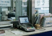 Corea del Sur regulará stablecoins en su ley de divisas Terminal de pago digital junto a formularios de cambio en un mostrador de remesas (imagen generada por IA)